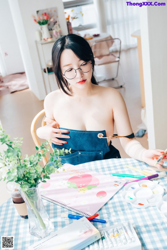 A woman sitting at a table with a bunch of art supplies.
