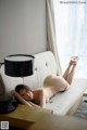 A naked woman laying on a couch next to a lamp.