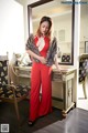 A woman in a red jumpsuit standing in front of a mirror.