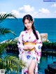 A woman in a white kimono standing next to a pool.