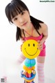 A young girl holding a smiley face balloon sculpture.