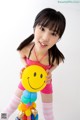 A young girl holding a smiley face balloon sculpture.