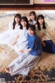 A group of young women sitting on a rug in a room.