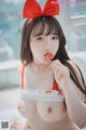 a woman in a red and white bikini eating a piece of cake