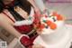 A woman in a santa claus outfit holding a cake.