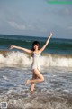 A woman in a white bathing suit standing in the ocean.