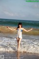 A woman in a white and blue bathing suit standing in the ocean.