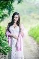 A woman in a white dress and pink shawl posing for a picture.