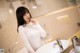 A woman standing in front of a bathroom sink.