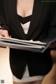 A woman in a black suit holding a folder.