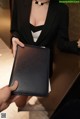 a woman in a black suit holding a black folder