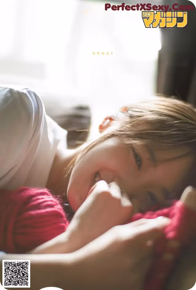 A woman laying on top of a bed next to a window.