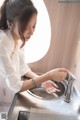 A woman is washing her hands in a sink.