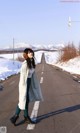 A woman standing on the side of a road in the snow.