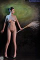 A naked woman holding a broom in her hand.