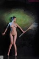 A nude woman holding a broom in her hand.