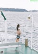 A woman standing on the deck of a boat looking out at the water.