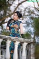 A woman in a blue dress and black gloves standing on a railing.