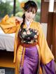 A woman in a yellow and purple kimono posing for a picture.