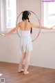 A young girl in a white leotard and blue skirt holding a hula hoop.