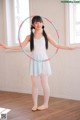 A young girl in a white leotard holding a hula hoop.