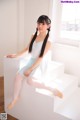 A young ballerina sitting on the steps of a white building.