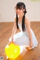 A woman in a white dress sitting on a yellow ball.