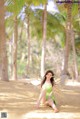 A woman in a green dress sitting on a sandy beach.