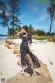 A woman standing on a rock on the beach.