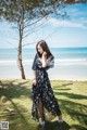 A woman standing on a grassy field next to the ocean.