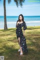 A woman standing on a grassy field next to the ocean.