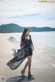 A woman walking on a beach in a black dress.