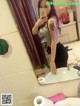 A woman taking a selfie in a bathroom mirror.