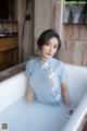 A woman in a blue dress sitting in a bathtub.