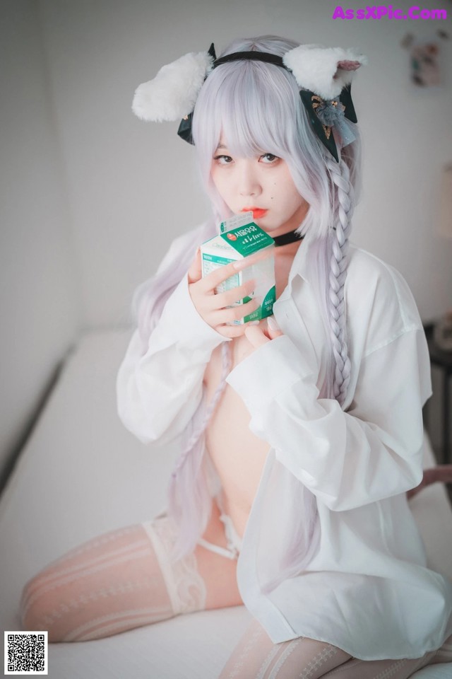 A woman sitting on a bed holding a box of milk.