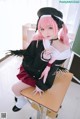 A woman with pink hair sitting on a desk.