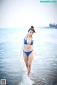 A woman in a blue bikini standing in the ocean.