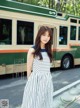 A woman in a striped dress standing in front of a bus.