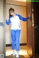 A woman in a blue and white track suit standing in front of a door.