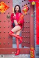 A woman in a red lingerie posing in front of a red door.