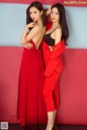 Two women in red dresses posing for a picture.