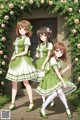 A group of three girls in green and white dresses.