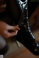 A close up of a person's hand holding a pair of black boots.