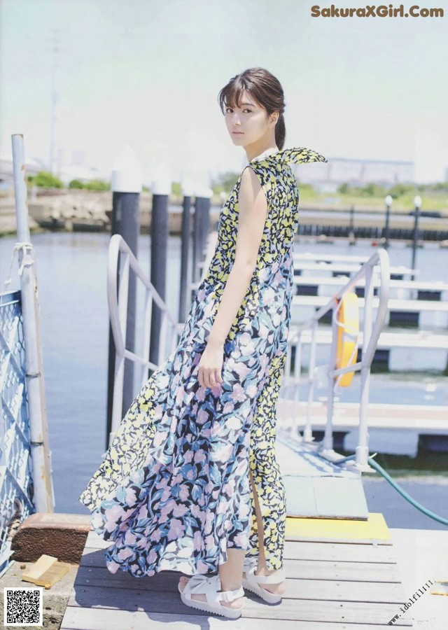 A woman standing on a dock next to a body of water.