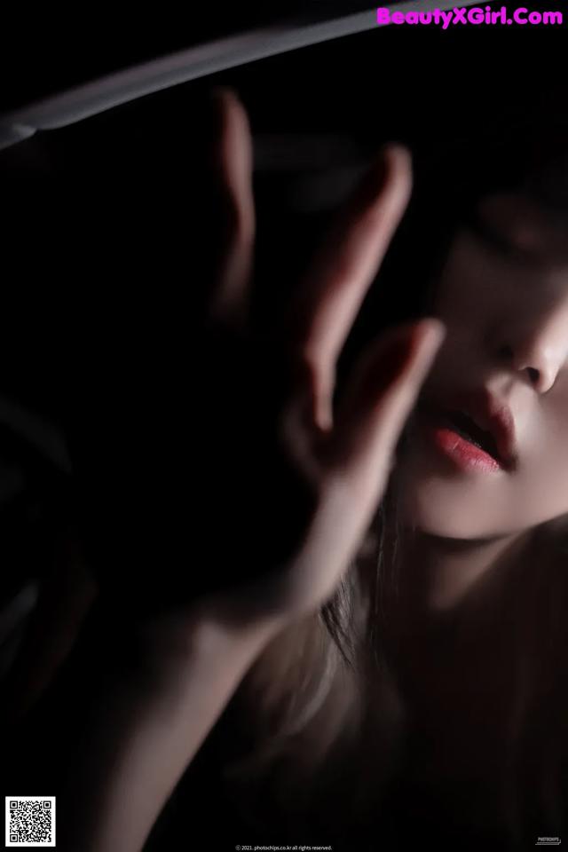A woman with her hand on her face in the dark.