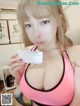 A woman in a pink bra holding a business card.