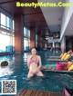 A woman in a pink bikini standing in a pool.