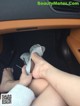 A woman's feet in a car with a pair of silver shoes.