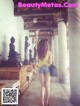 A woman standing in front of a buddha statue in a temple.