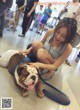 A woman is petting a bulldog on a leash.